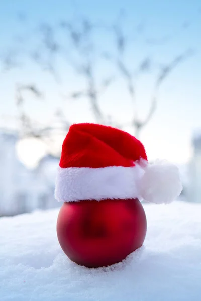 Χριστουγεννιάτικο φόντο με κόκκινο καπέλο santa σε λευκό χιόνι. — Φωτογραφία Αρχείου