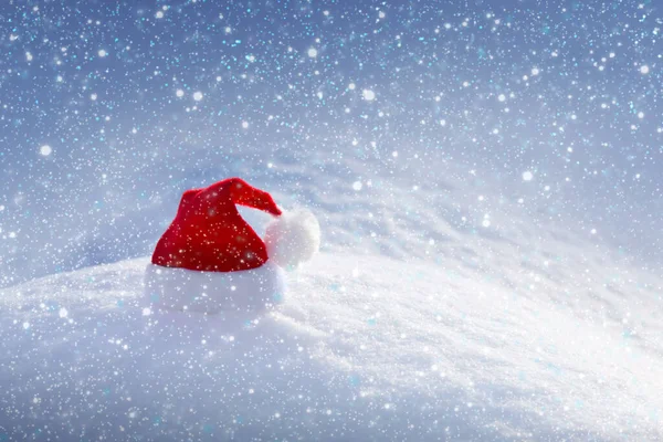 Beyaz kar üzerinde kırmızı Noel Baba şapkası olan Noel arkaplanı. — Stok fotoğraf
