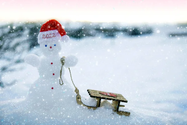 Boże Narodzenie tło z bałwana i drewna sanki stoją w białym śniegu. — Zdjęcie stockowe