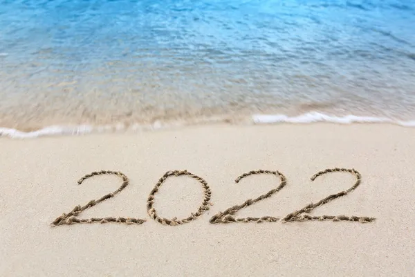 Año Nuevo 2022 escrito en la playa de arena caribeña con olas marinas . — Foto de Stock