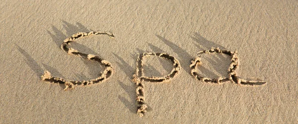 Слово Спа написано на песке. Оздоровительный фон. — стоковое фото