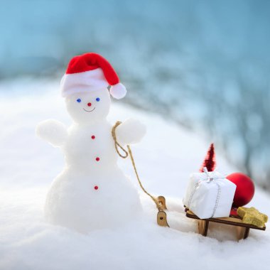 Kardan adam ve hediyelerle dolu Noel arkaplanı beyaz karda duruyor..