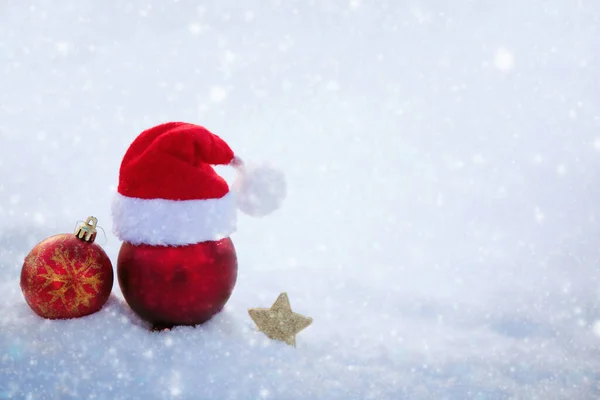 Χριστούγεννα φόντο με κόκκινο καπέλο Σάντα και διακοσμήσεις σε λευκό χιόνι. — Φωτογραφία Αρχείου