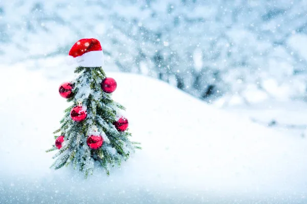 Χριστούγεννα φόντο με κόκκινο καπέλο Σάντα και έλατο σε λευκό χιόνι. — Φωτογραφία Αρχείου