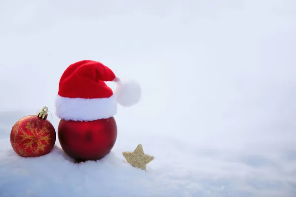 Різдвяний фон з червоним капелюхом Санти та прикрасами на білому снігу . — стокове фото