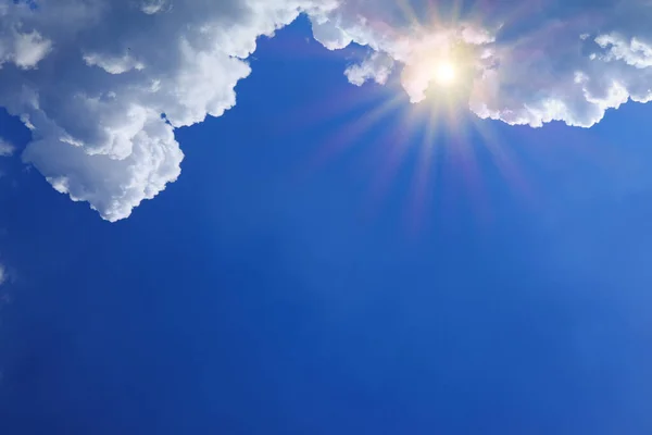 Zonnestralen en grote wolken op blauwe zomerhemel. — Stockfoto