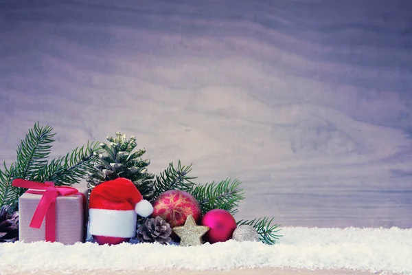 Шляпа Санта-Клауса и подарочная коробка на снегу . — стоковое фото