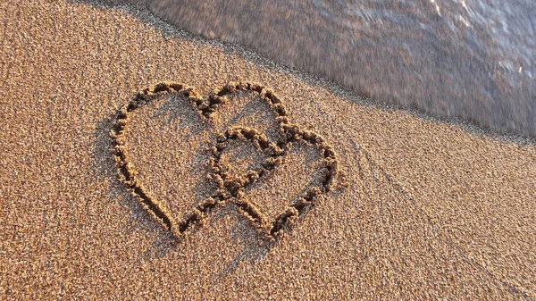 Two hearts drawn on brown sand of paradise beach — Stockfoto