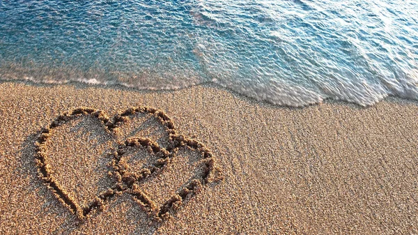 Two hearts drawn on brown sand of paradise beach — Stock Photo, Image