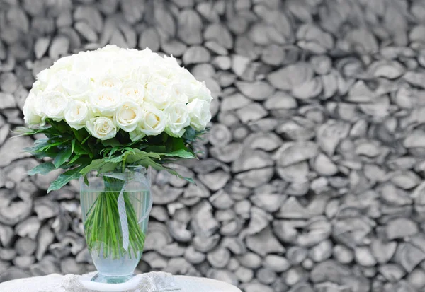 Bukett av vita rosor i en glasvas på grå bakgrund. — Stockfoto