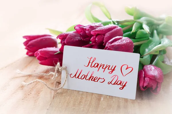 Karta Happy Matki Day z fioletowymi tulipanami na tle drewna. — Zdjęcie stockowe