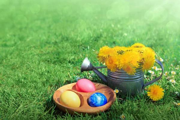 Coloridos huevos de Pascua en el prado de primavera fresca y jarra de agua. — Foto de Stock