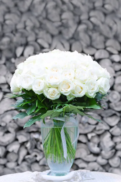 Kytice z bílých růží ve skleněné váze na šedém pozadí. — Stock fotografie