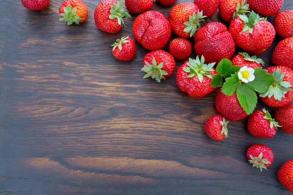 Fresas y flores sobre fondo de madera marrón. — Foto de Stock