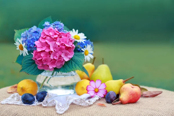 Buquê de flores coloridas em vaso de vidro e frutas frescas misturadas  . — Fotografia de Stock