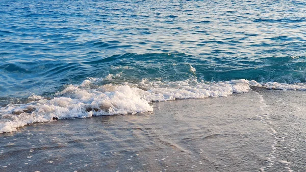 Morze błękitne fale łamią się na piaskowej plaży. — Zdjęcie stockowe