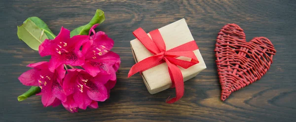 Mothers day card hand with heart and gift on brown wooden background. — Zdjęcie stockowe