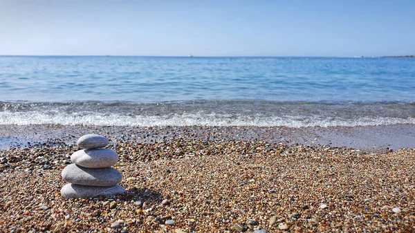 Pyramid of sea pebbles, composed by the sea. The object is in focus, the background is blurred.