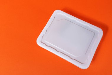Turuncu zemin üzerinde beyaz plastik bir fast food tabağı - üst görünüm, izole