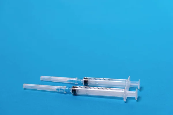 Mavi arka planda iki adet tek kullanımlık plastik şırınga, ön plan, açık açıklık, arka plan bulanıklığı, bokeh