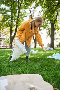 Parkı temizlerken koruyucu eldiven giyen aktif çevreci.
