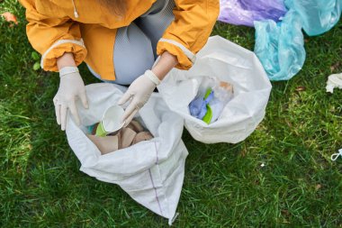 Dışarıdaki çöpleri toplayıp farklı torbalara koyan bir kadın.
