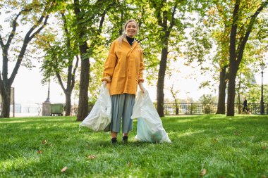 İki büyük çöp torbası taşıyan ve çöpleri toplamaya yardım eden gönüllü bir kadın.