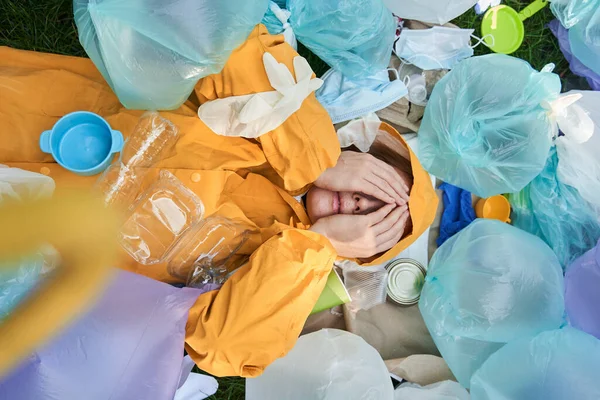 Etrafı çöp yığınlarıyla çevrili bir kadın gözlerini kapattı ve stresli hissetti.