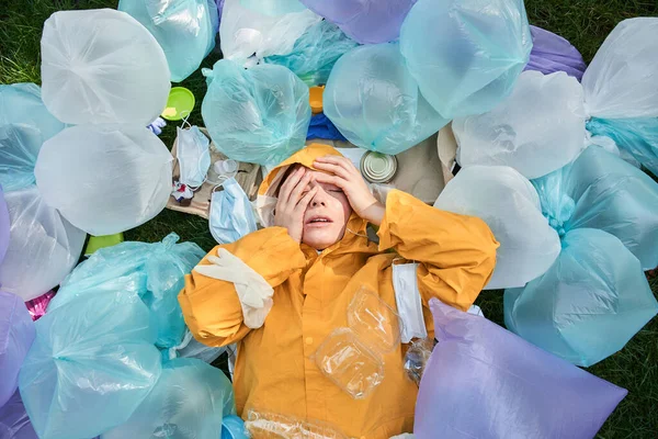 Etrafı çöp yığınlarıyla çevrili bir kadın gözlerini kapattı ve stresli hissetti.