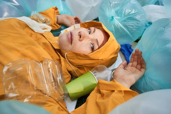 Atık bir şekilde yatarken kameraya bakan beyaz bir kadın.