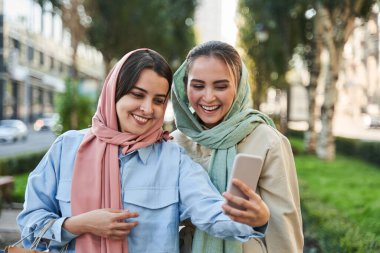 İslamcı bayan arkadaşlar şehirde kalırken akıllı telefondan selfie çekiyorlar.