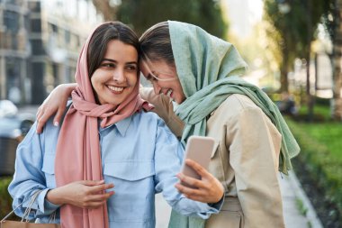 Mutlu milenyum dişileri akıllı telefon kamerasıyla selfie çekiyor.