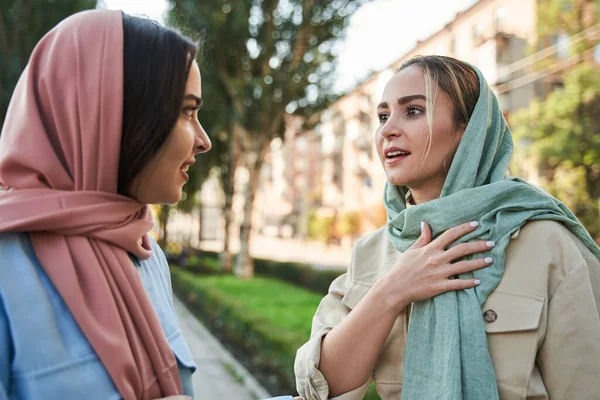 Dos chicas musulmanas sinceras usando hiyabs charlando emocionalmente —  Fotos de Stock