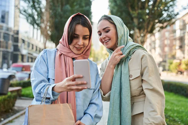 Heureuses filles islamiques dans le hijab s'amuser et faire du selfie dans la rue pendant la marche — Photo