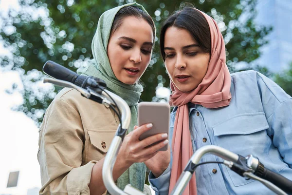 Lányok iszlám vallás segítségével app közelében városi kerékpár állomás, szociális hálózat — Stock Fotó