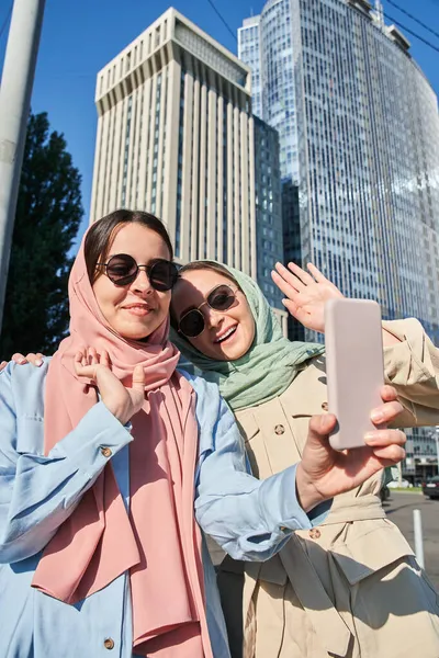 Iszlám női barátok integetett, miközben videohívás okostelefonon — Stock Fotó