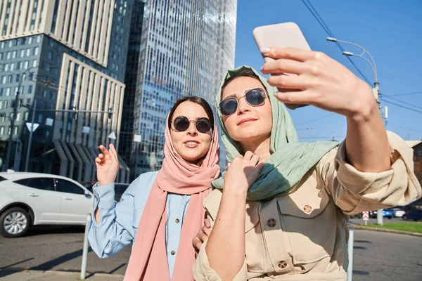 Millenniumi nők viselnek fejkendő gazdaság video hívás a barátaikkal, és rámutatva — Stock Fotó