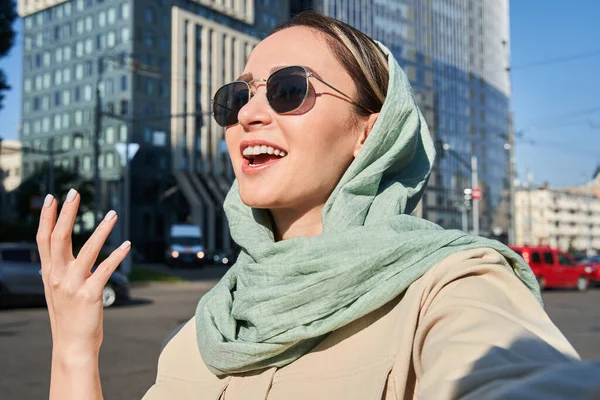 Muszlim lány mosolyog és csevegés valakivel, miközben tartja videohívás utazás közben — Stock Fotó