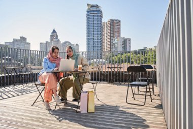 Kadın telefonda konuşuyor ve paralel olarak bayan arkadaşına bir şeyler söylüyor.