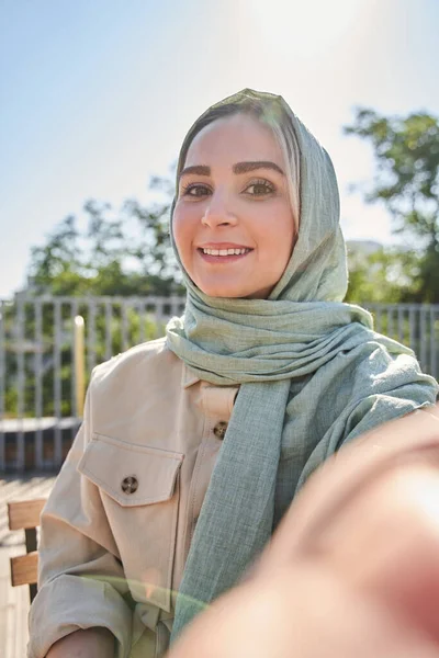 Árabe chica en hijab disparo a sí misma en el selfie cámara vista y sonriente alegre —  Fotos de Stock