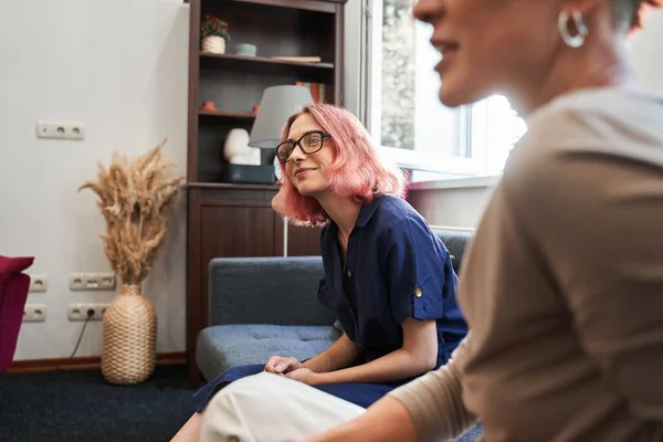 분홍색 머리를 하고 소파에 앉아서 의사를 뚫어지게 바라보는 레즈비언 여성 — 스톡 사진