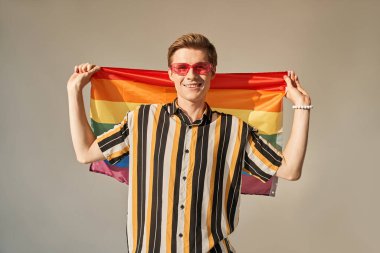 Gay gururlu genç adam LGBT Gökkuşağı bayrağı kameraya bakıyor