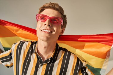 Bej arka planda lgbt bayrağı tutan cinsiyet değiştiren adam