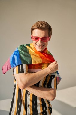Gururlu genç adam omuzlarında LGBT Gökkuşağı bayrağı