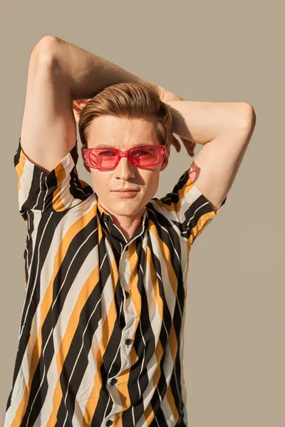 Mann im perfekten Look und rosa Sonnenbrille posiert in hinreißender Pose vor der Kamera — Stockfoto