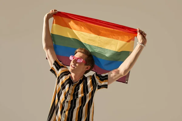 Male person standing and hand holding the rainbow flag at the raised hands — Stock Photo, Image