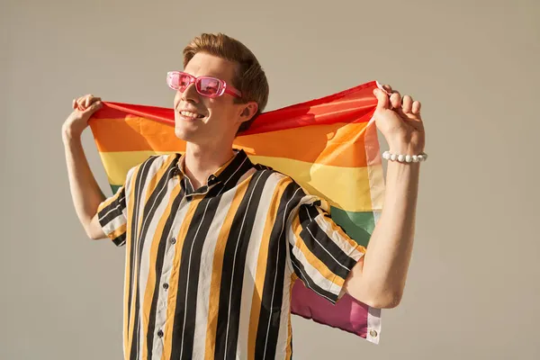 Activista hombre sosteniendo bandera de arco iris para desfile orgullo lgbt y mirando hacia otro lado — Foto de Stock