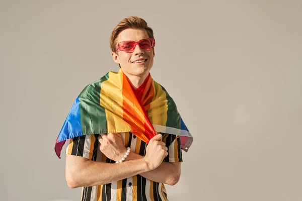 Bisexuální muž aktivista nosí Duhovou vlajku pro průvod pýchy Igbt a dívá se do kamery — Stock fotografie