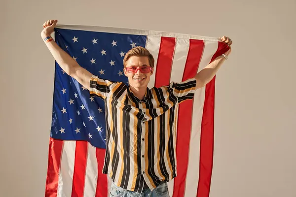 Hombre patriótico de pie con la bandera americana con la pared beige en el fondo — Foto de Stock