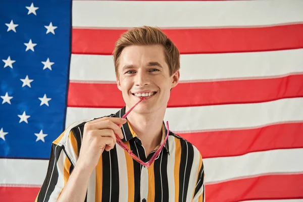 Americký občan usměvavý zub při pózování s vlajkou USA v pozadí — Stock fotografie